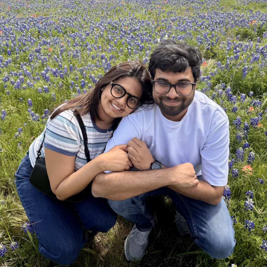 Manasi and Arush crouching together in a field of wildflowers