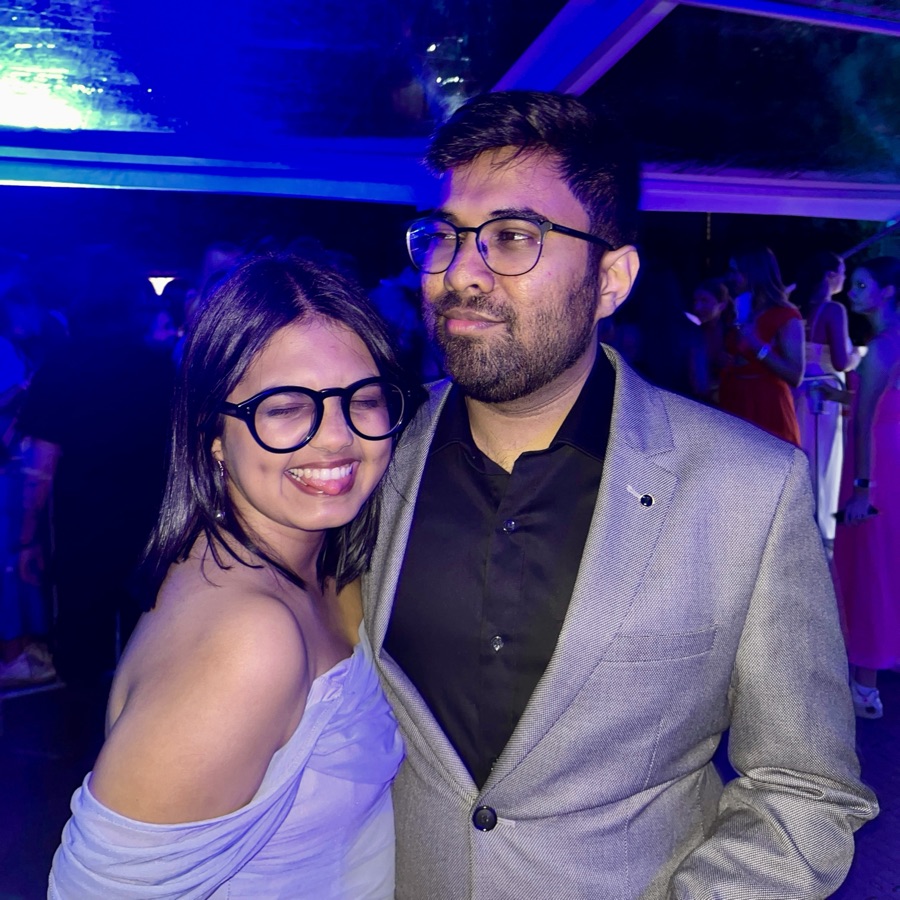Manasi smiling and leaning on Arush's shoulder at an evening party